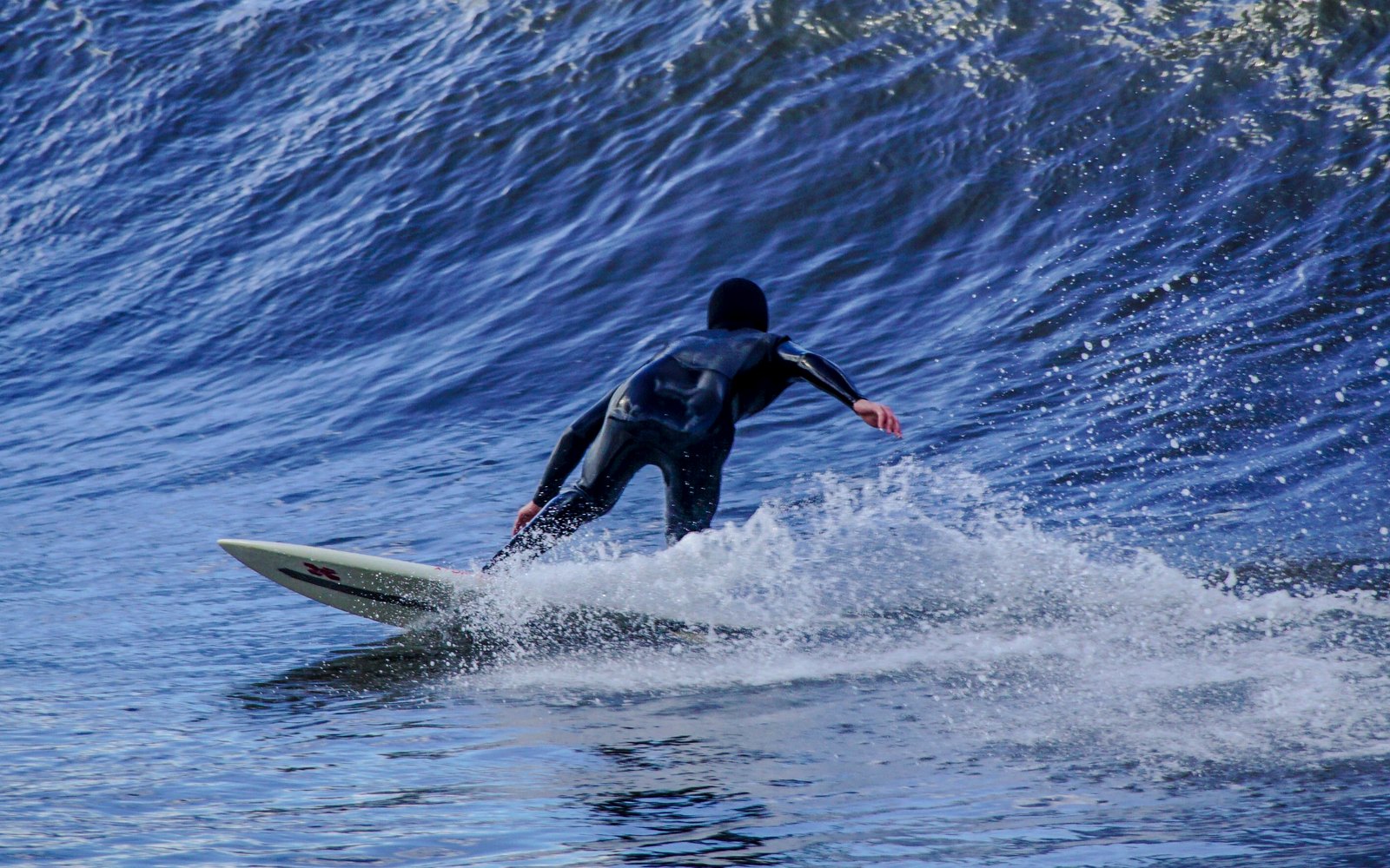Stock photograph of a surfer carving across a blue ocean wave